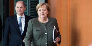 Finanzminister Olaf Scholz läuft hinter Bundeskanzlerin Angela Merkel in einen Raum