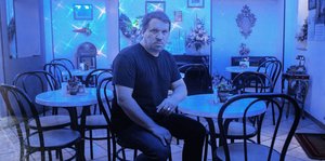 Der Musiker Rob Mazurek sitzt in einem blau beleuchteten Raum