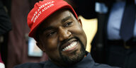 Rapper Kanye West trägt breit grinsend eine "Make America Great Again"-Kappe.