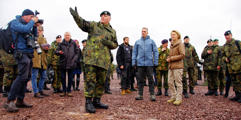 Mehrere Menschen, einige davon in Uniform, stehen auf steinigem Boden