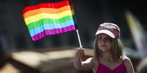 Ein Mädchen schwenkt eine Regenbogen-Flagge