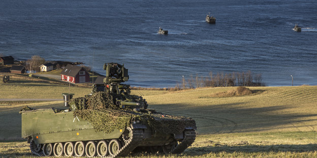 Ein Panzer fährt die Küste Trondheims entlang, im Hintergrund fliegen Kampfjets.