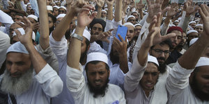 In Pakistan demonstriert eine große Gruppe Männer mit erhobenen Händen