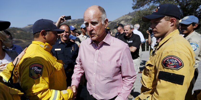 Jerry Brown schüttelt einen Feuerwehrmann die Hand