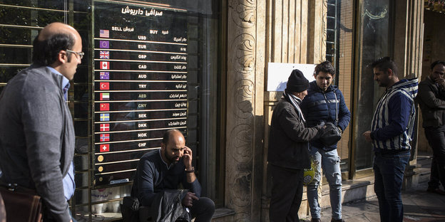Teheran: Menschen warten neben einer Tafel, die die Wechselkurse der Währungen im Zentrum Teherans anzeigt