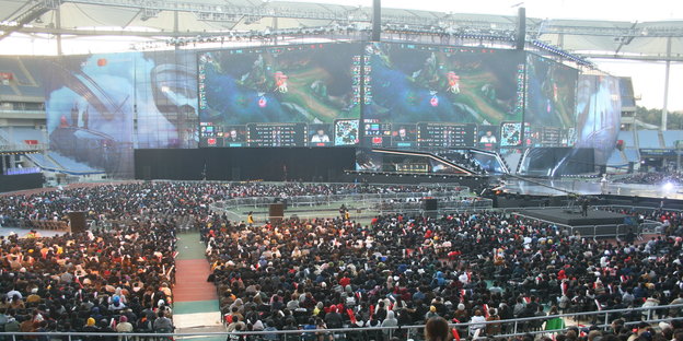 In einem Stadion sitzen tausende Zuschauer, auf riesigen Bildschirmen werden Computerspiele übertragen