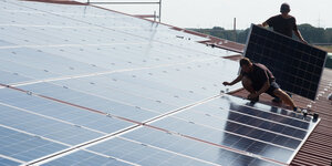 Arbeiter montieren Solarzellen auf einem Dach