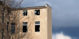 mehrstöckiges Haus mit kaputten Fenstern vor blauem Himmel