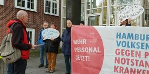 Personen stehen hinter Transparent vor dem Hamburger Arbeitsgericht