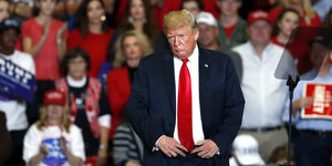 Donald Trump steht mit missmutigem Gesicht vor einem Auditorium