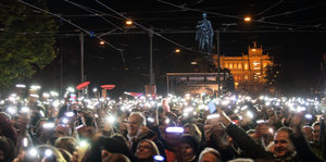Menschen in der Dunkelheit halten ihre leuchtenden Smartphones hoch