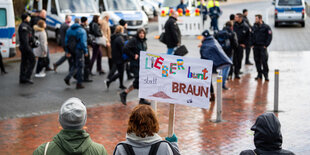 Demonstranten mit einem Schild mit der Aufschrift "Lieber bunt statt braun".