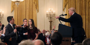 Menschen in einem Saal. Donald Trump zeigt auf einen Mann, der neben einer Frau steht