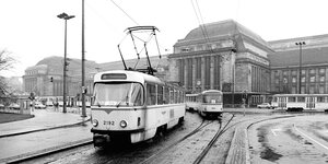 Eine schwarz-weiße Straßenbahn fährt über Schienen vor dem Leipziger Bahnhof.