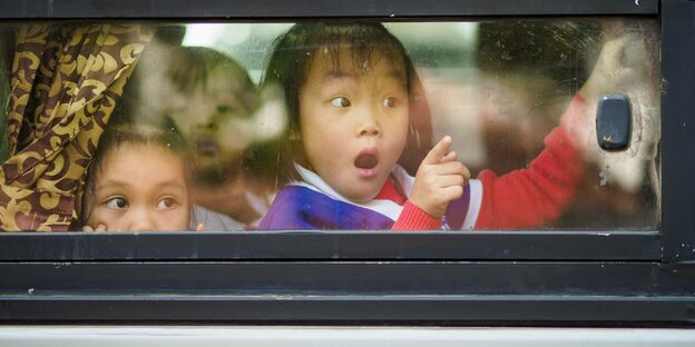 Kinder schauen aus einem Busfenster heraus