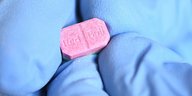 Eine rosa Ecstasy-Pille auf einem blauen Gumminhandschuh