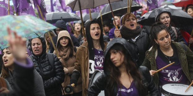 Frauen mit Trommeln und Regenschirmen auf einer Straße