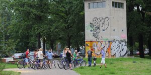 Einige Radfahrer besichtigen einen ehemaligen Wachturm an der ehemaligen deutsch-deutschen Grenze mitten in Berlin