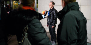 Heiko Maas steht vor der Presse mit Lederjacke und weißen Turnschuhen