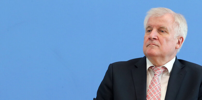 Horst Seehofer mit Anzug und Krawatte vor hellblauem Hintergrund