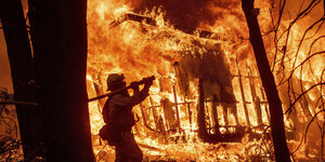 Ein Feuerwehrmann vor einem brennenden Haus