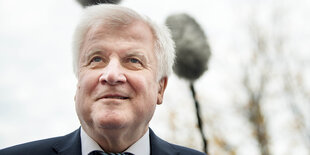 Nahaufnahme von Horst Seehofer im Freien, über ihm hängen Mikrofone mit Windschutz