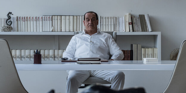 Toni Servillo als Silvio Berlusconi an einem Schreibtisch sitzend