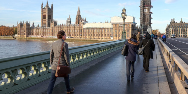 Menschen gehen über die Westminster Bridge in London, der Himmel ist weit und blau