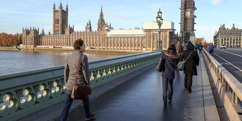 Menschen gehen über die Westminster Bridge in London, der Himmel ist weit und blau