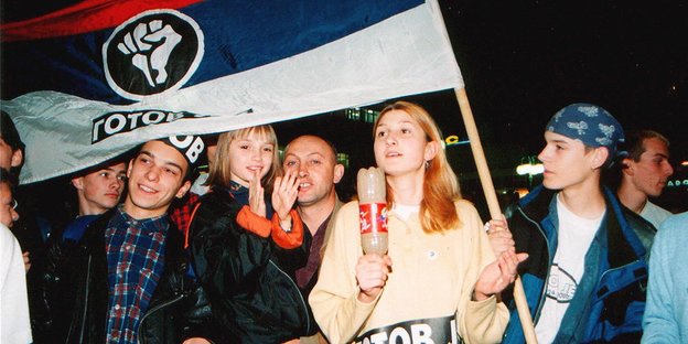 Studenten tragen eine Flagge in den Farben Serbiens, darauf ist eine geballte Faust und der Schriftzug der Bewegung "Otpor" zu sehen