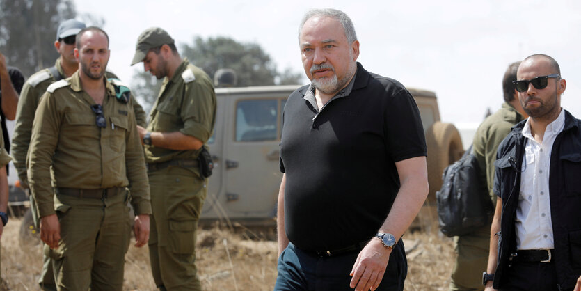 Lieberman unter freiem Himmel, um ihn herum mehrere Männer, einige davon in Uniform