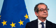 Ein Mann mit Brille sitzt vor einer Europa-Fahne