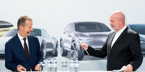 VW-Chef Diess und der Betriebsratsvorsitzende Osterloh bei der Pressekonferenz vor einem Plakat, das vier sportliche VW-Modelle zeigt