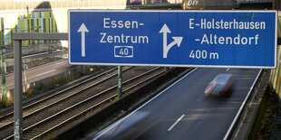 Eine Autobahn, über der ein blaues Autobahnschild hängt