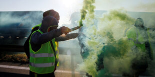 Ein Demonstrant gestikuliert aus einem Auto heraus, während Fahrer und Biker Straßen und Autobahnen blockieren.