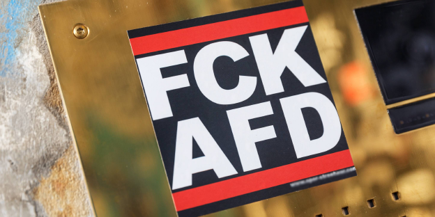 Ein Aufkleber mit der Aufschrift „FCK AFD“ klebt auf einer goldenen Oberfläche