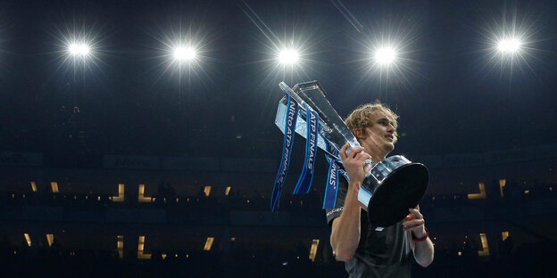 Der Tennisspieler Alexander Zverev steht mit seinem Pokal in einer Arena