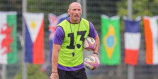 Der Rugbyspieler Gareth Thomas steht mit Trikot und zwei Bällen unter dem Arm auf einem Sportplatz