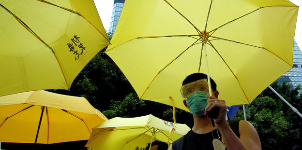 EIn Mann trägt einen gelben Regenschirm