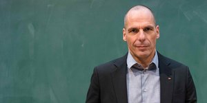 Varoufakis steht vor einer grünen Wand