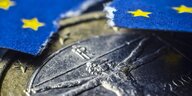Eine Euromünze, darüber eine eingerissen Europaflagge