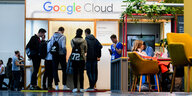 Junge Menschen stehen auf einer Messe an einem Google-Stand