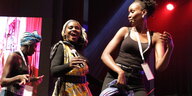 Eine afrikanische Kümnstlerin mit zwei Tänzerinnen auf einer Bühne