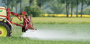 Ein Landwirt fährt mit einer Dünger- und Pestizidspritze über ein Feld