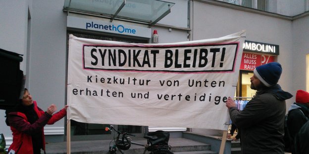 Menschen halten ein Transparent mit der Aufschrift "Syndikat bleibt" inder Hand Menschen halten ein Transparent mit der Aufschrift "Syndikat bleibt" inder Hand