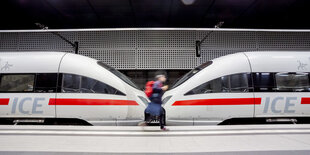 n Mann geht im Berliner Hauptbahnhof an einem ICE entlang.