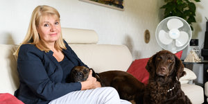 Eine Frau sitzt mit zwei Hunden auf einem Sofa