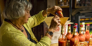 Eine Frau gießt Tomatensaft durch einen Trichter