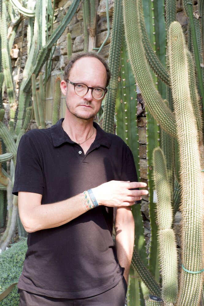 Carl von Siemens, ein Mann mit Halbglatze und Brille, steht neben großen Kaktuspflanzen