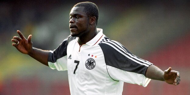 Gerald Asamoah, ein Mann mit dunkler Hautfarbe hat ein Deutschland-Trikot an und breitet beide Arme aus